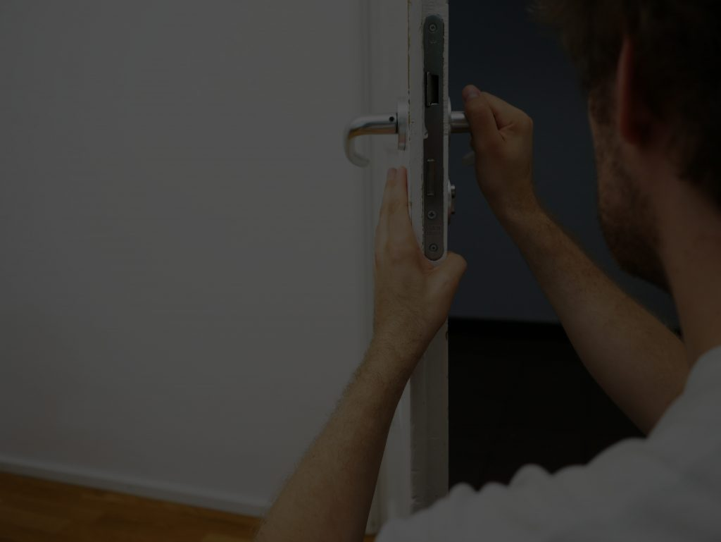 A person installs a door lock, focusing on aligning the mechanism with the doorframe. This image illustrates home improvement tasks.