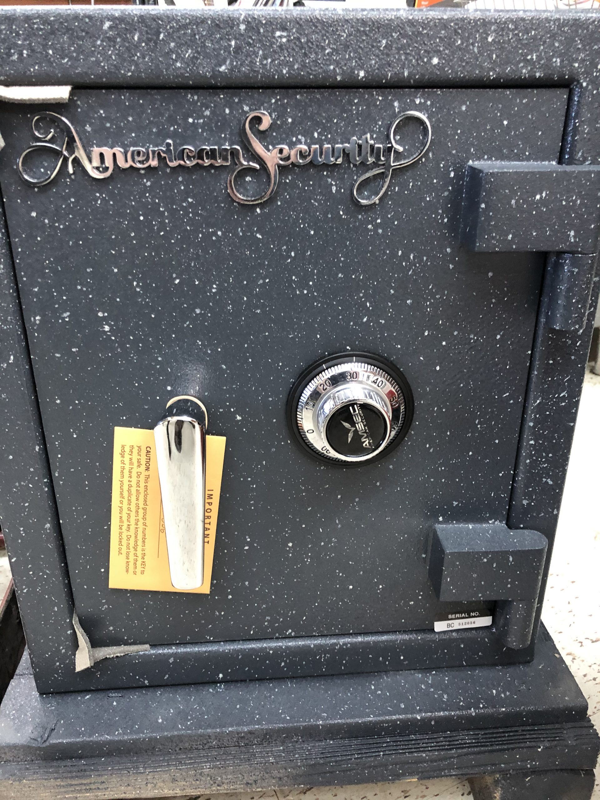 Black security safe featuring a combination lock and a notice labeled "IMPORTANT." The safe is marketed by American Security, highlighting its protective purpose.